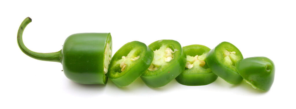 A green jalapeno on a white background, sliced with each piece laying in a line.